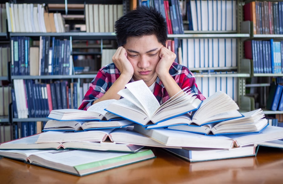 Asian Male Student Tired and Stressed with Readings